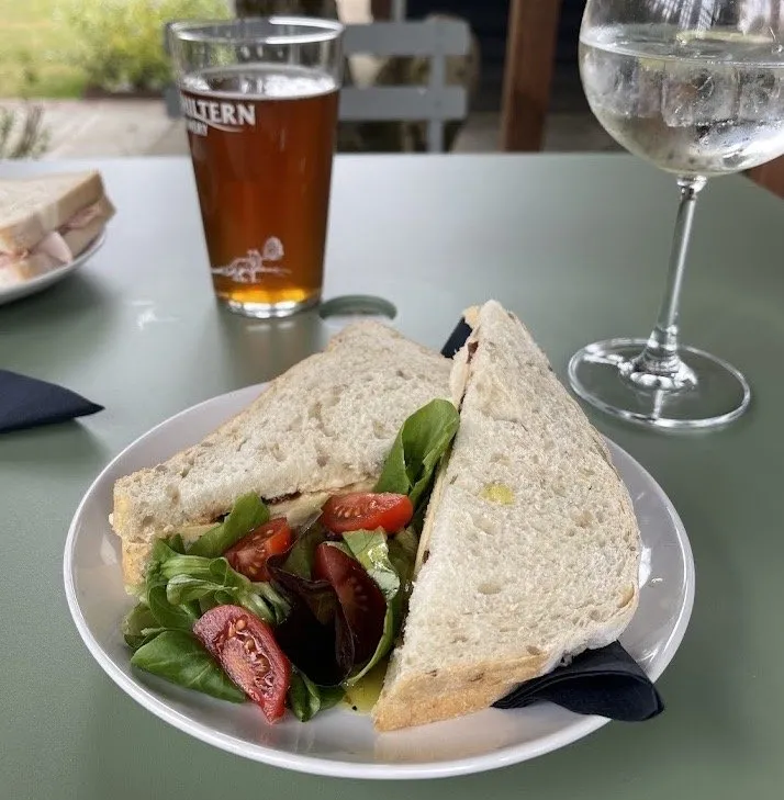 A freshly made granary sandwich with a side salad on a garden table, next to a pint of Chiltern ale