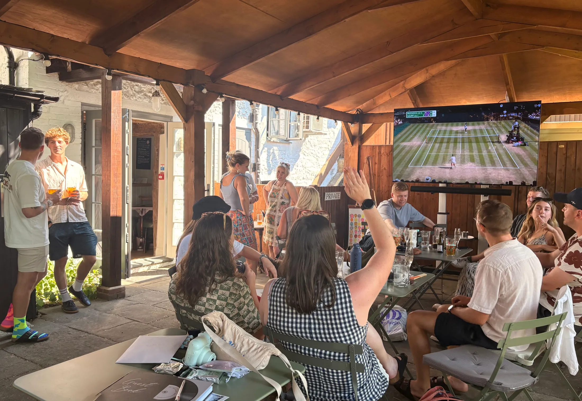 A busy afternoon under the pergola, friends gathered with drinks around the tables