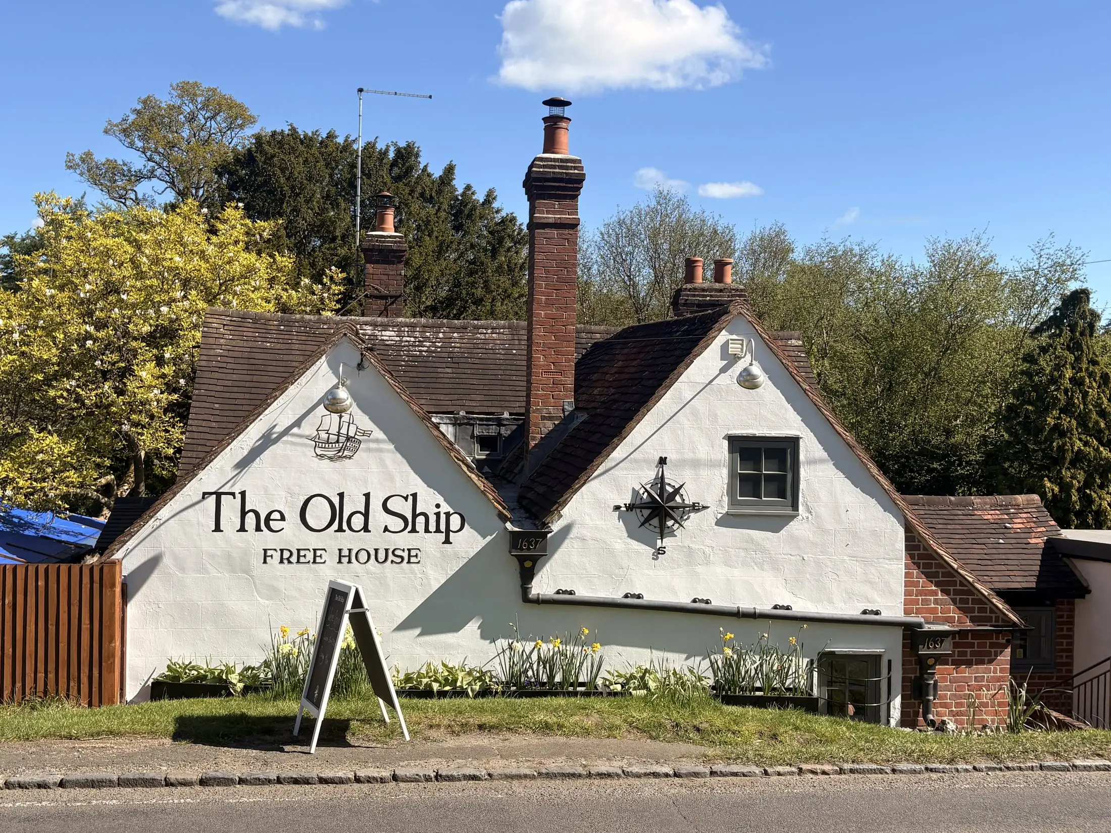 The Old Ship free house, the whitewashed 17th-century pub in Cadmore End, with its painted sign, under a blue sky