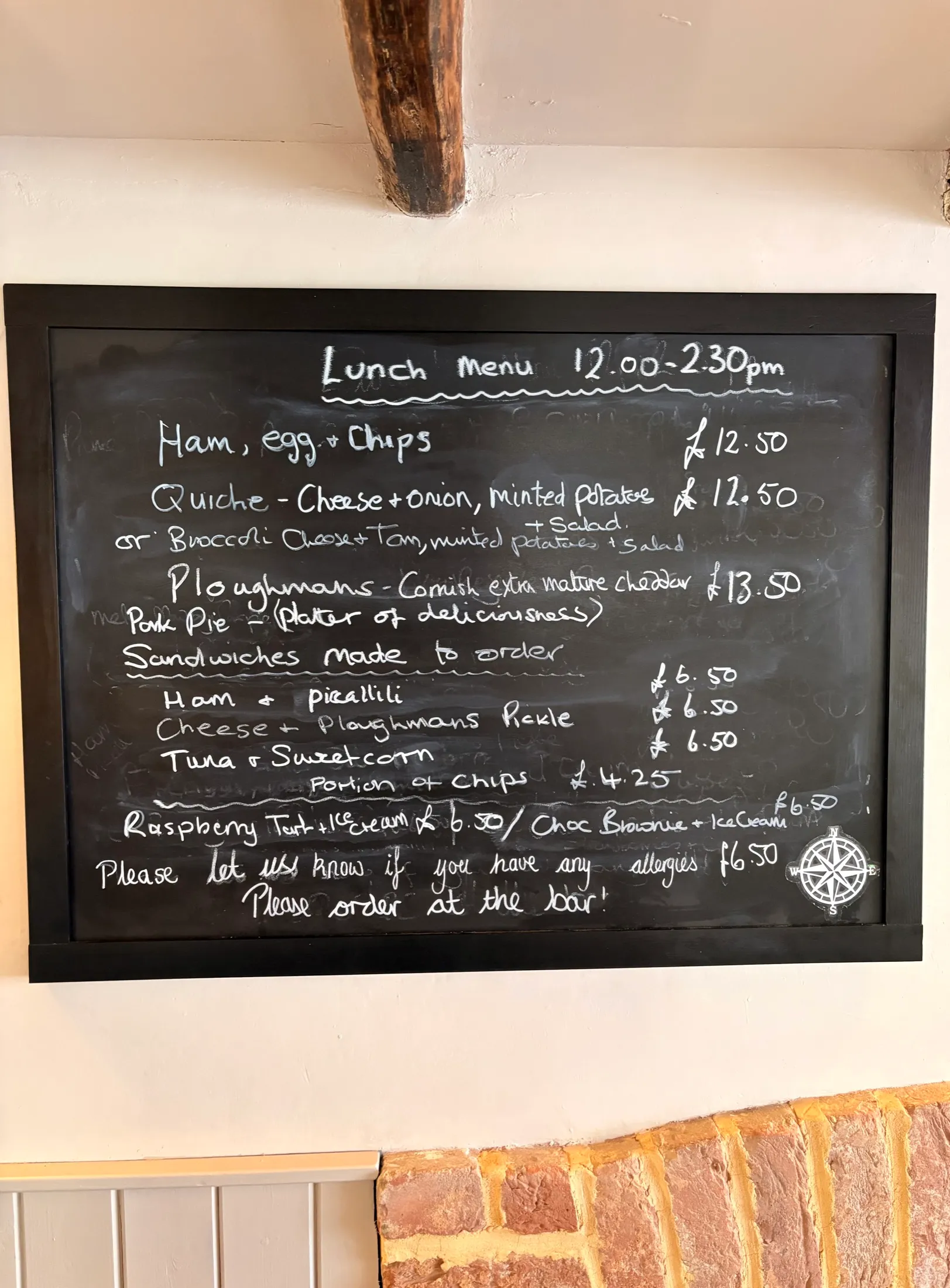 A chalkboard lunch menu at The Old Ship listing ham egg and chips, quiche, ploughman's, pork pie and made-to-order sandwiches